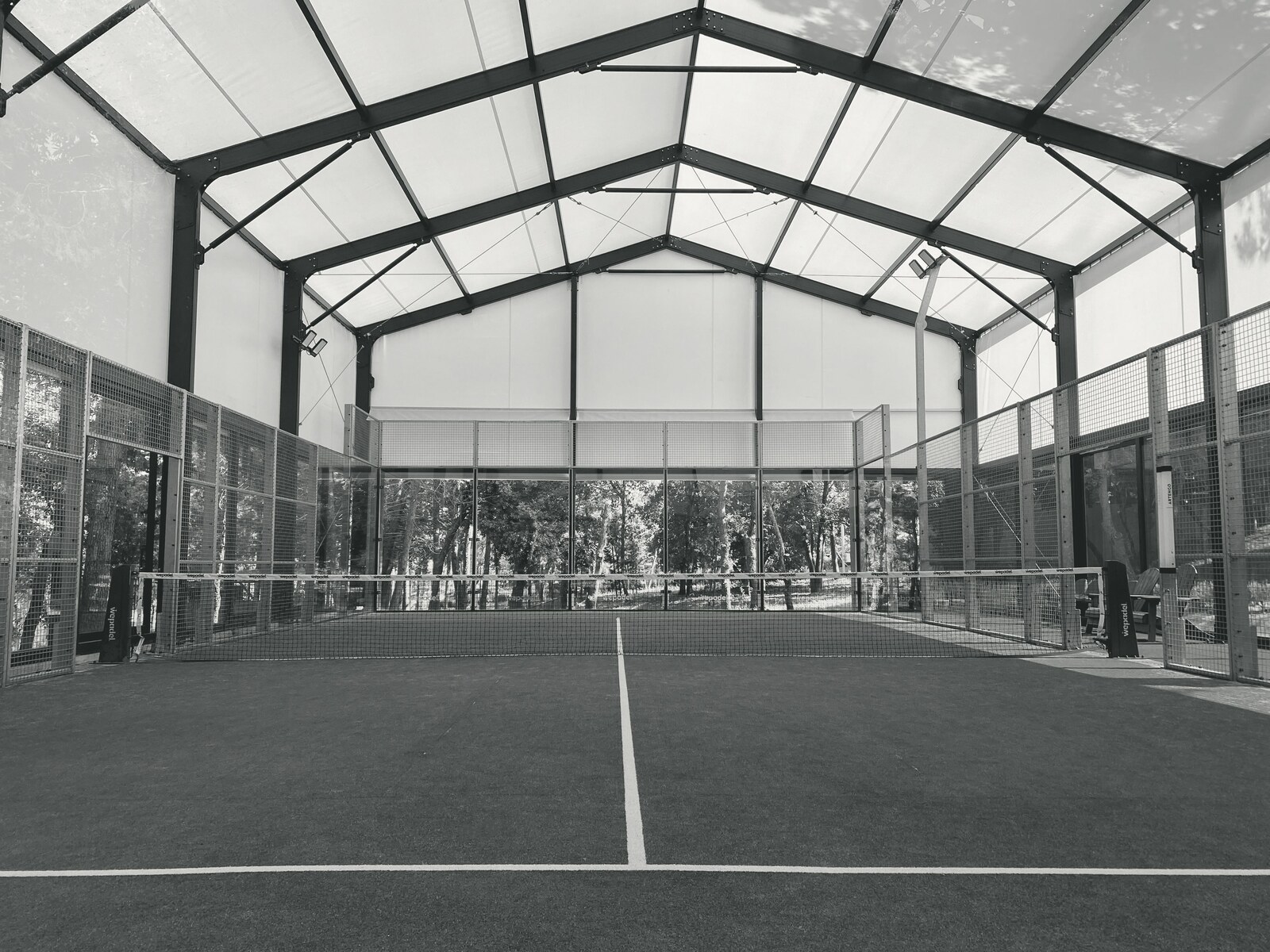 Indoor padel court with net and glass walls